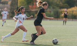 women's soccer player running with ball