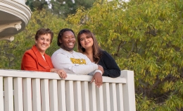 professor and two business students posing together on a balcony